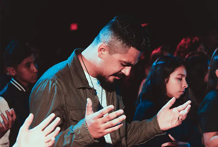 A man is praying in front of other people.